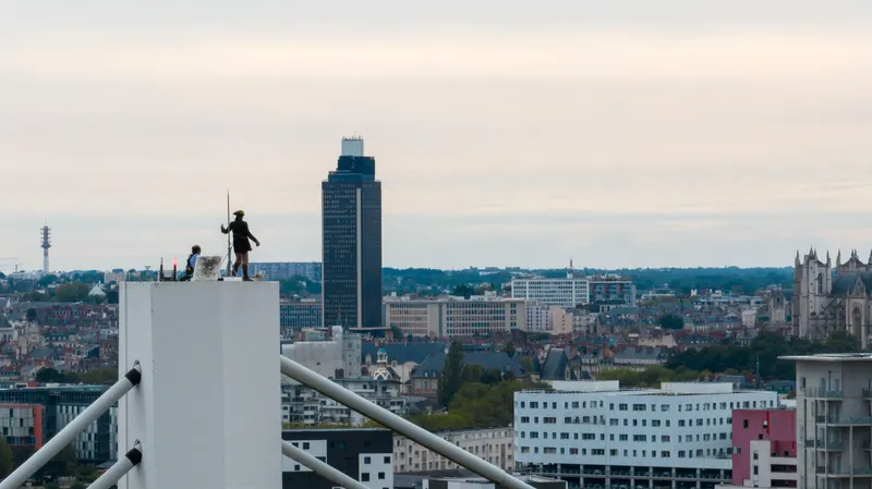 Un artiste debout au sommet du pylône du pont, à 54 mètres, la ville de Nantes derrière lui