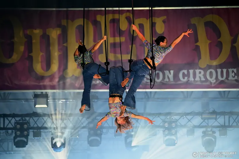 Le trio en sangles, tête en bas devant la banderole géante du festival