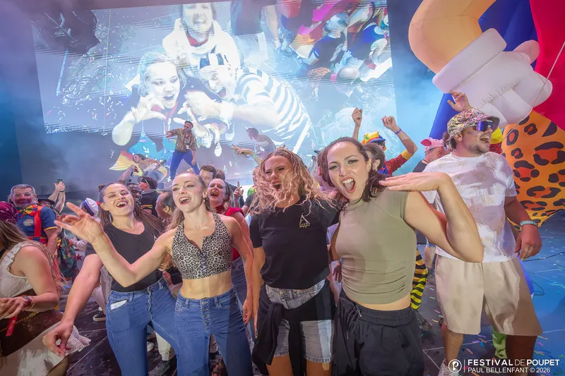 La troupe en fête sur scène avec le public, écran géant derrière
